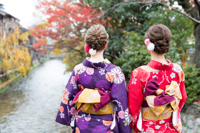 Two women wearing kimono while overlooking the Shirakawa River in Kyoto