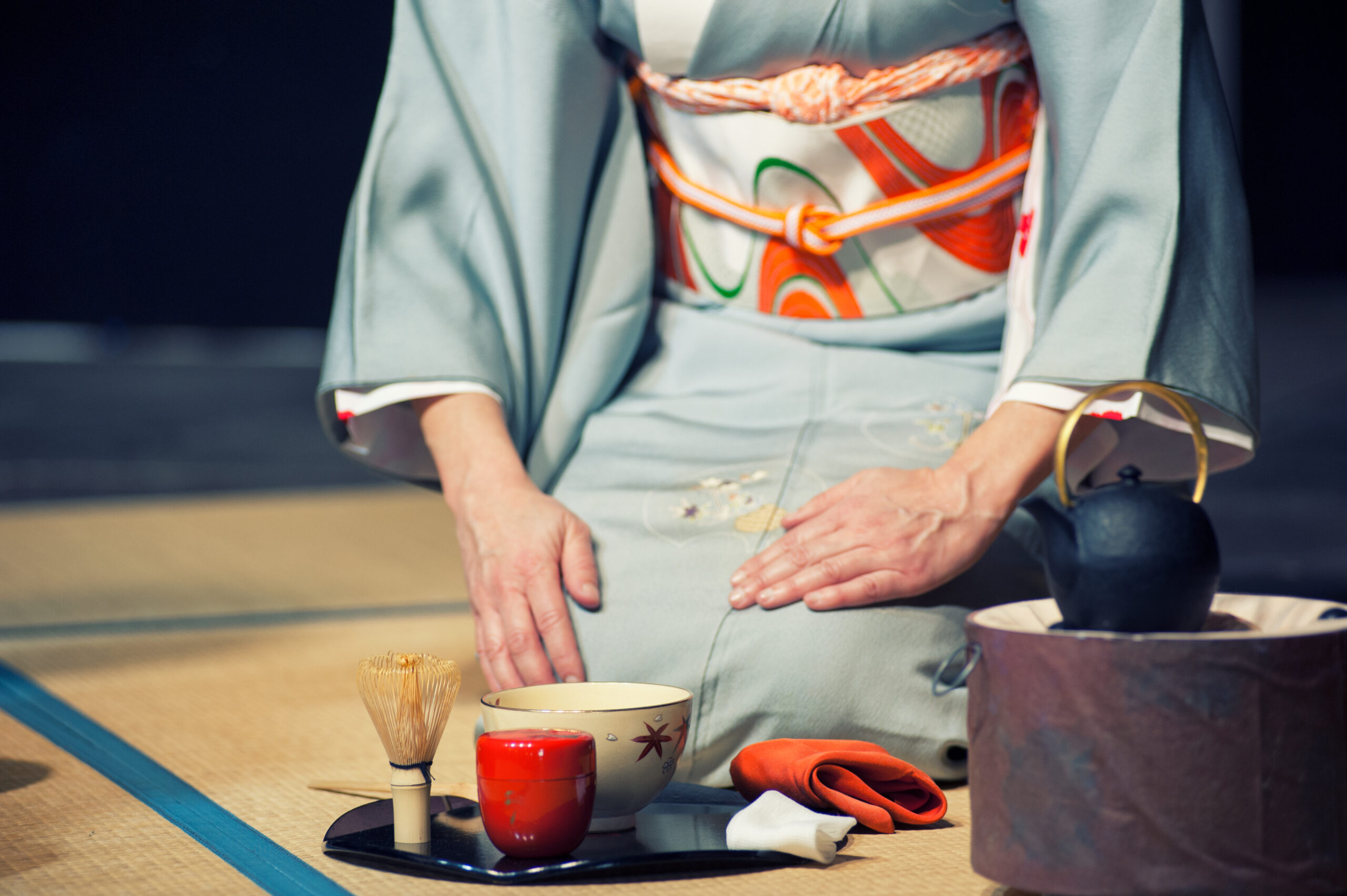 Japanese woman with light blue kimono holding a teacup, during the traditional tea ceremony